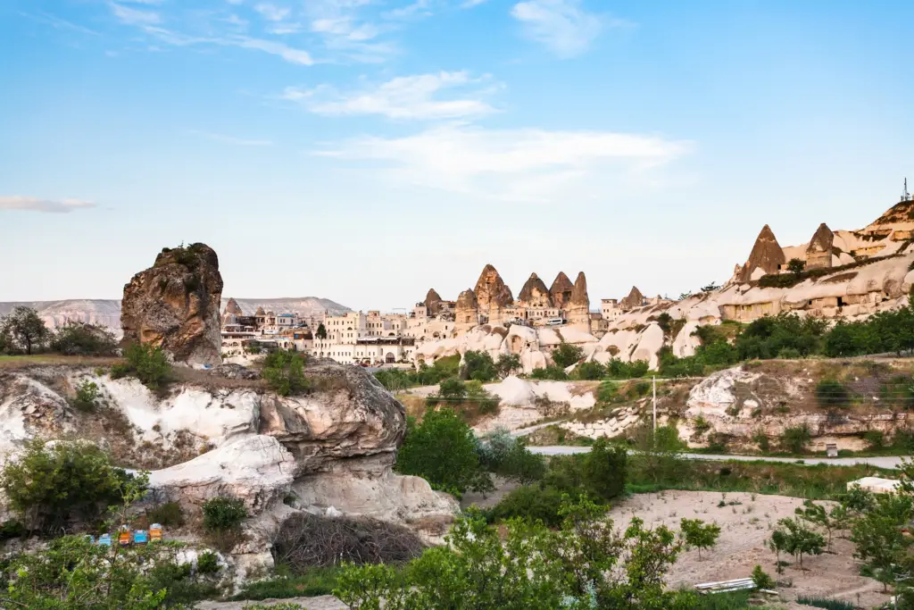 Goreme town with cave houses and chimney-topped rock behind, Cappadocia, Turkey