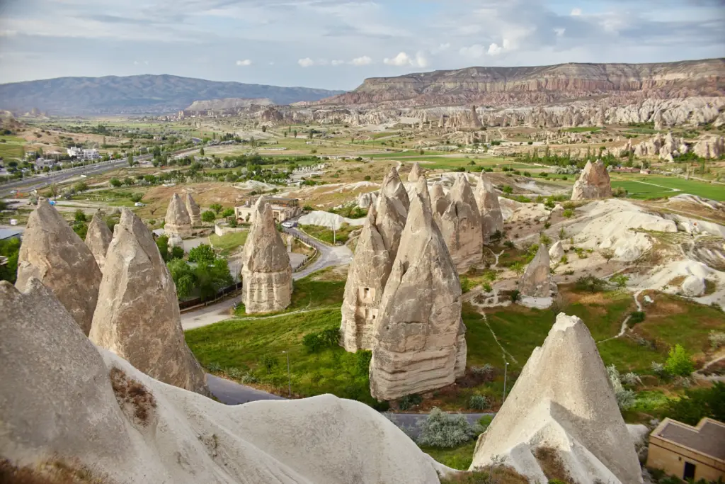 Fairy chimneys above the Goreme valley with the town and orchards below, Cappadocia, Turkey