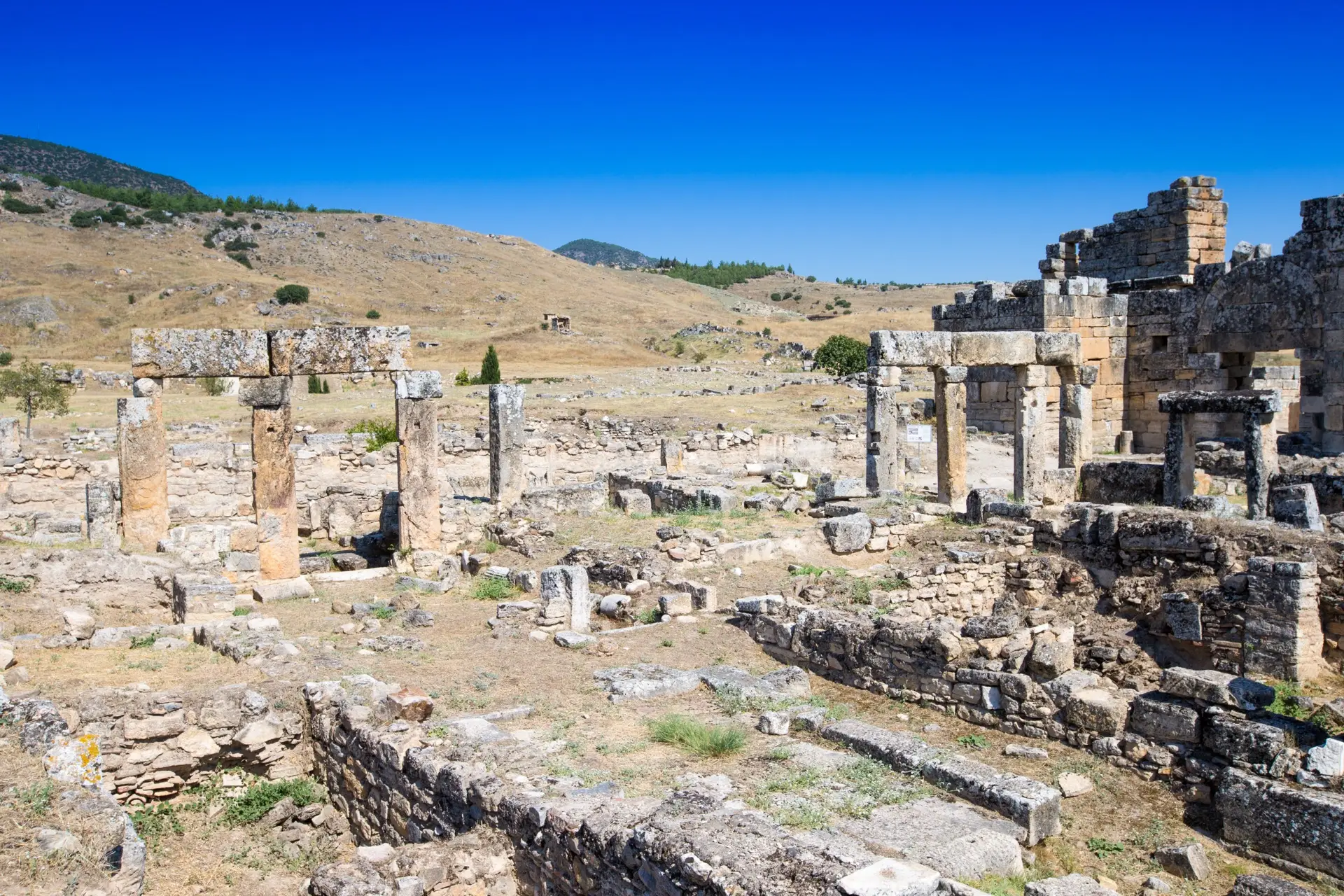 Hierapolis ruins on the open plateau above Pamukkale under a cloudless summer sky