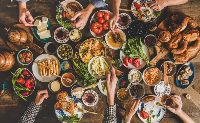 Turkish breakfast spread with cheeses, olives, honey, jams, simit and tea on a wooden table